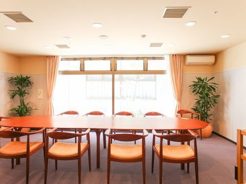 じゅうたん張りの部屋である。長テーブルに椅子が10脚ある。観葉植物もあり、温かい雰囲気のゲストダイニングである。