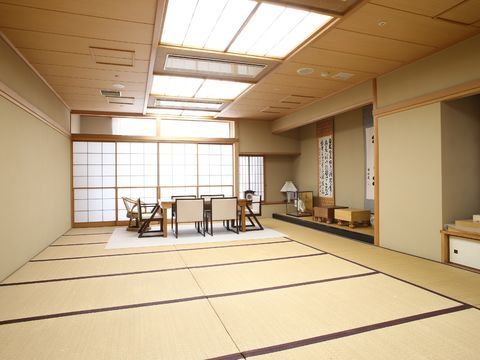 広々とした和室。床の間や掛け軸もあり、本格的な和室で落ち着いた雰囲気である。机と椅子も置かれている。
