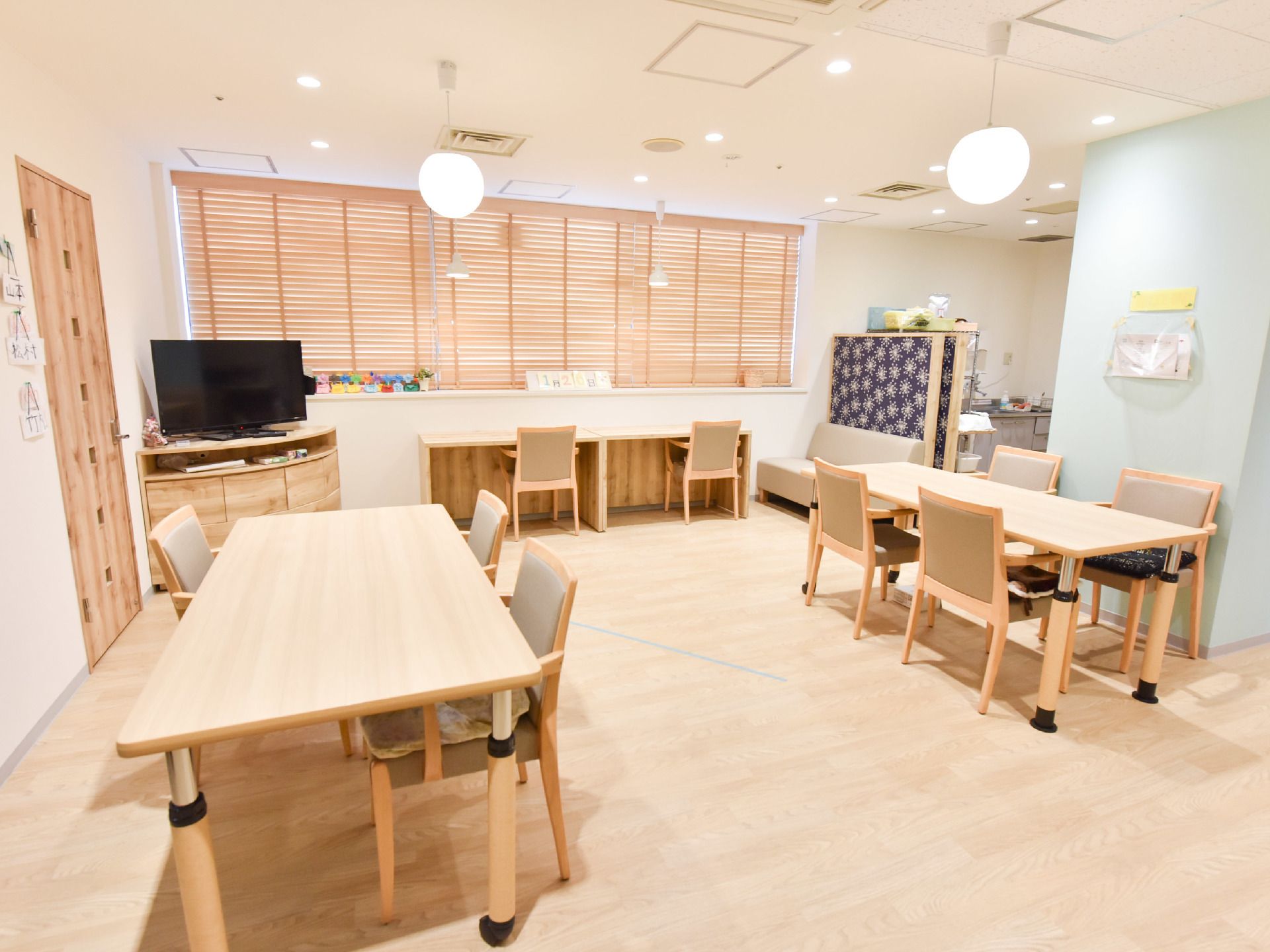 床が木目調で居心地のいい雰囲気を醸し出している。奥の方にはキッチンがあり、炊事や給仕等を行うことが出来る。