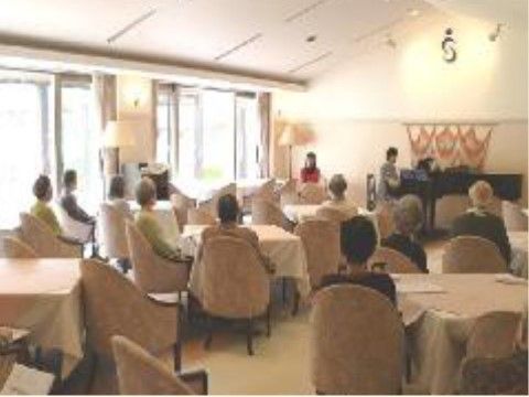 ゆったりとした椅子に座ってピアノ演奏を聴いている入居者様たち