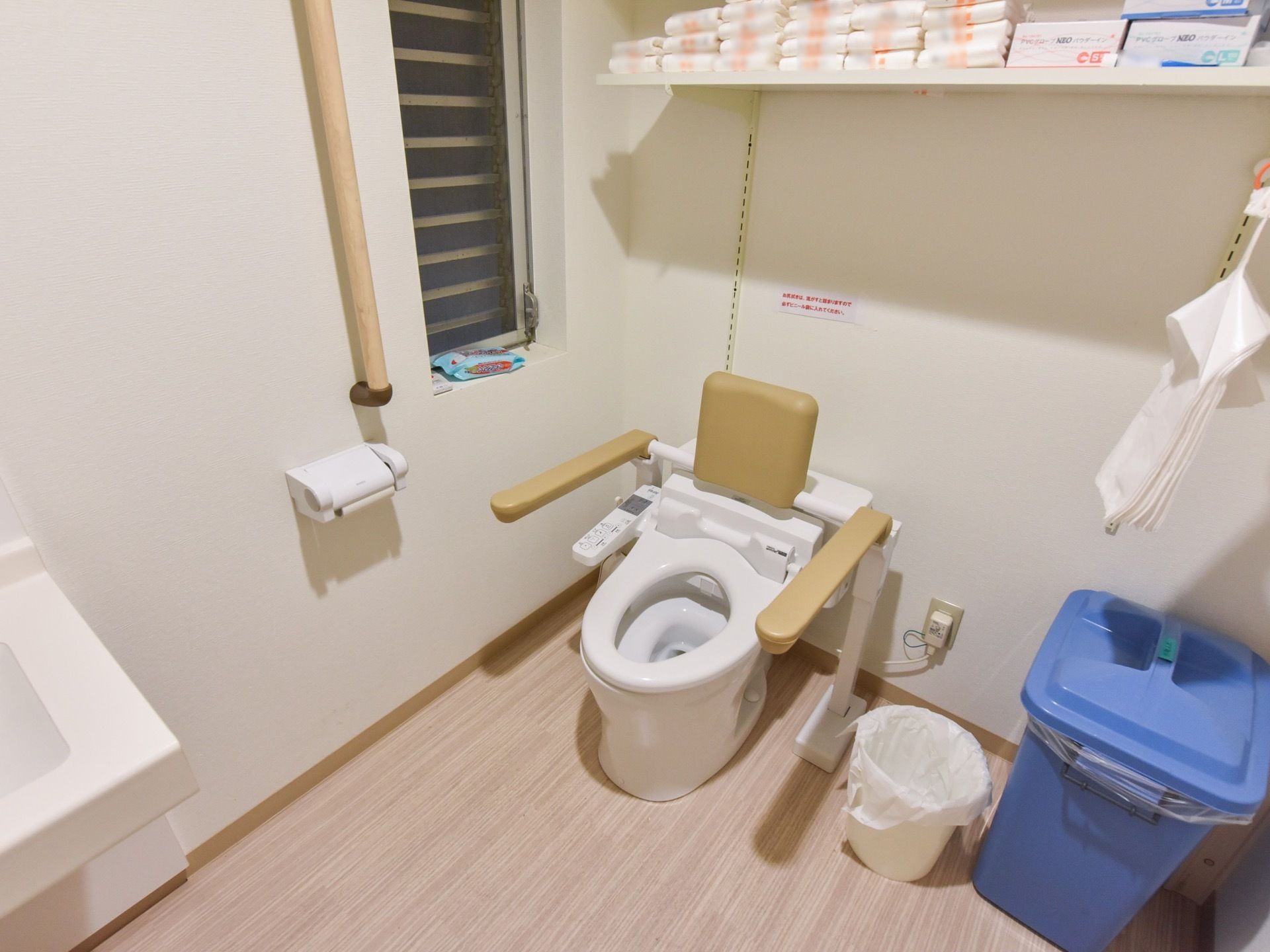 肘掛けと背もたれがついたトイレがある。壁には手すりが設置されている。移動スペースは広く確保されている。
