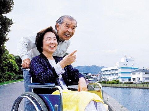 車椅子で外出をする高齢者と介助者