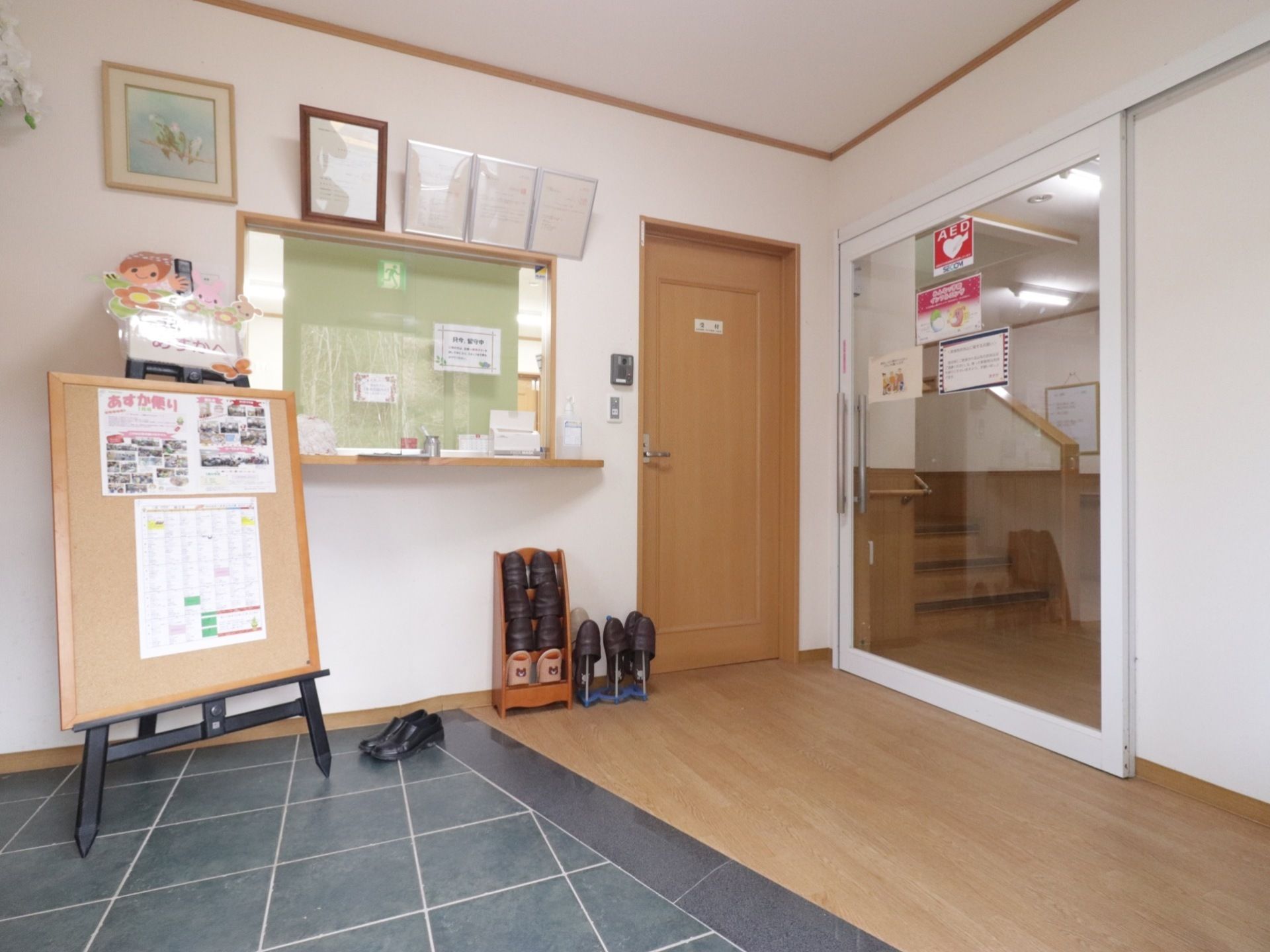玄関を入ってすぐに受付がある。受付の前には、お知らせが貼られた大きなボード、来訪者様用のスリッパが用意されている。