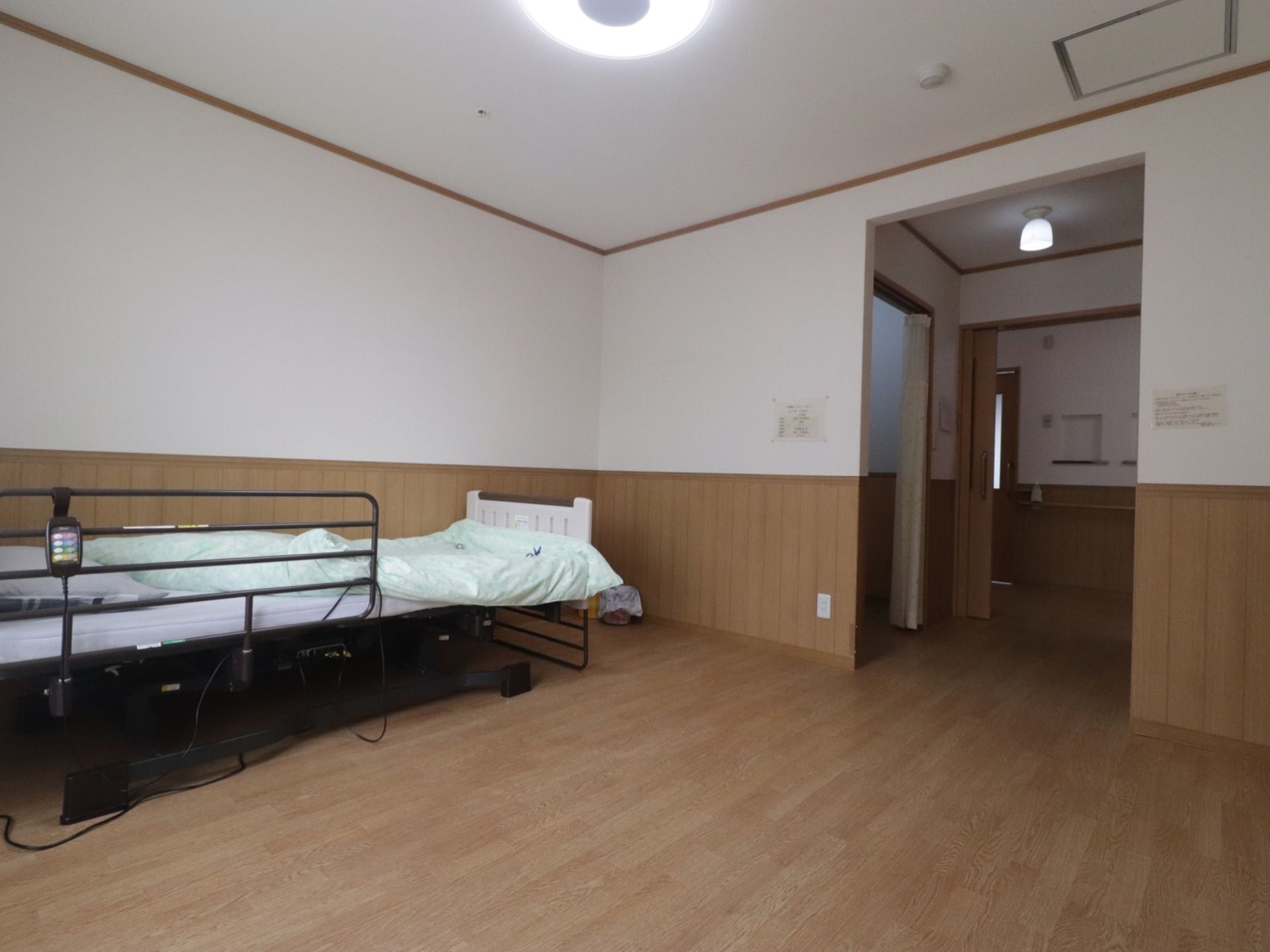 足元には段差がなく、広々としている。壁側にベッドが置かれている。入口のドアはスライド式で大きく開くようになっている。