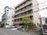 施設は病院の横にある茶色い鉄骨造りの５階建て建物である。玄関横には駐車場があり、片側には庭木が植えてある。