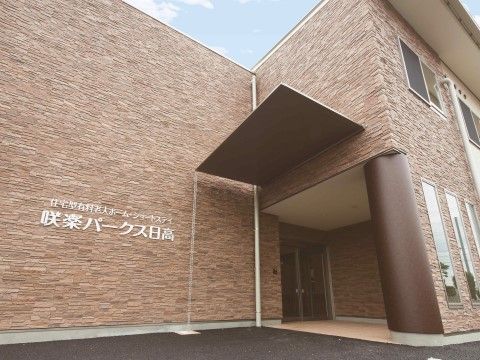 茶色を基調とした外壁を持つ２階建ての施設の玄関付近
