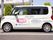 施設の駐車場の一角に配備された送迎車は、白を基調とした、清潔感のある色合いである。側面には施設名が明記されている。