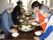 入居者様とスタッフがホットプレートを囲み生地を焼いている。おいしいおやつを楽しみながら入居者様同士の交流を深める場になっている。