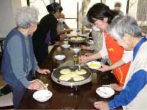 ホットプレートで料理を作っている高齢者と介護スタッフ。