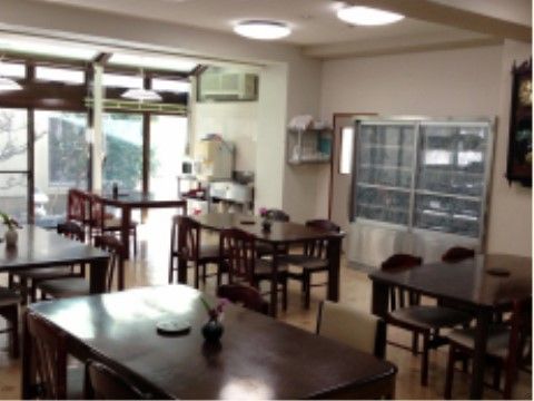 落着いた深い色合いのテーブルや椅子が並ぶ空間。大きな窓があり、窓からは庭の風景を楽しむことができる。