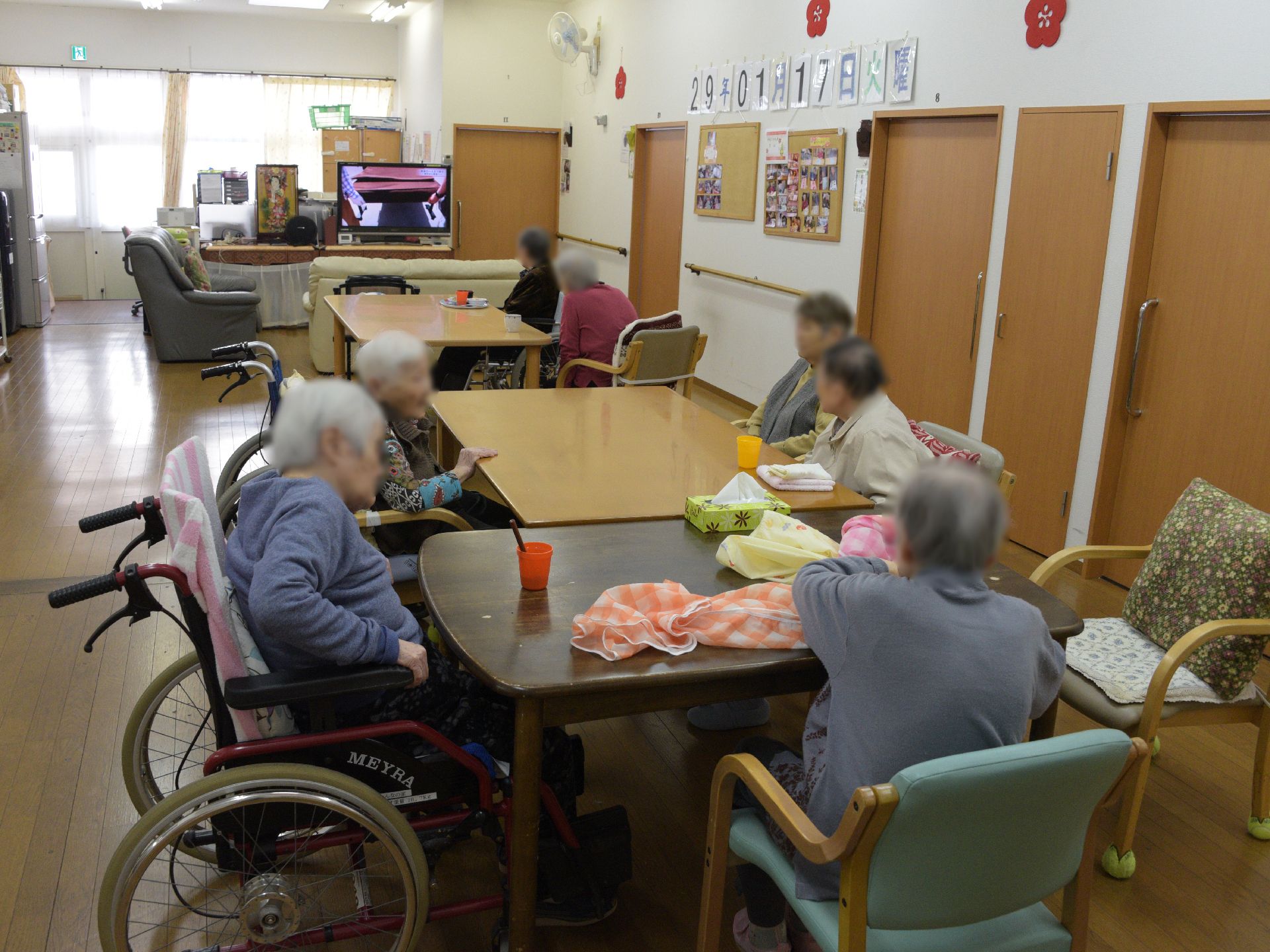 利用者同士が話をしたり、テレビを見たり、自由に過ごしている。椅子に座れる人だけでなく、車椅子を利用している人もいる。