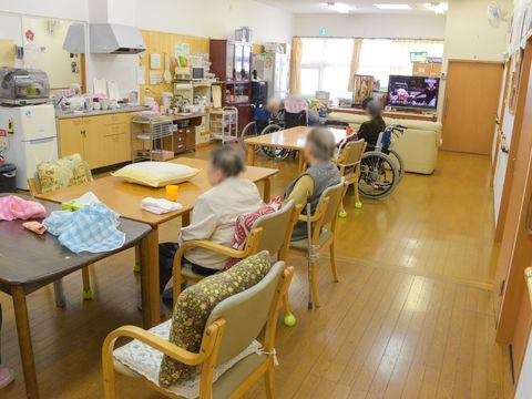 食堂にある、座面や背もたれにクッションが置かれた椅子に座っている入居者様たち