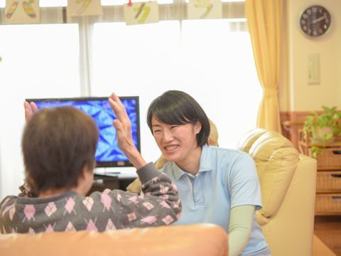 ソファに座っている女性入居者様に話しかけている女性スタッフ