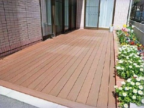 掃き出し窓から出ることができ、ふちに多くの花が咲いているウッドデッキ