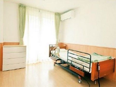 日当たりの良い居室である。リモコン付きの介護ベッドと白い引き出しが４段ついた洋服ダンスが置かれている。