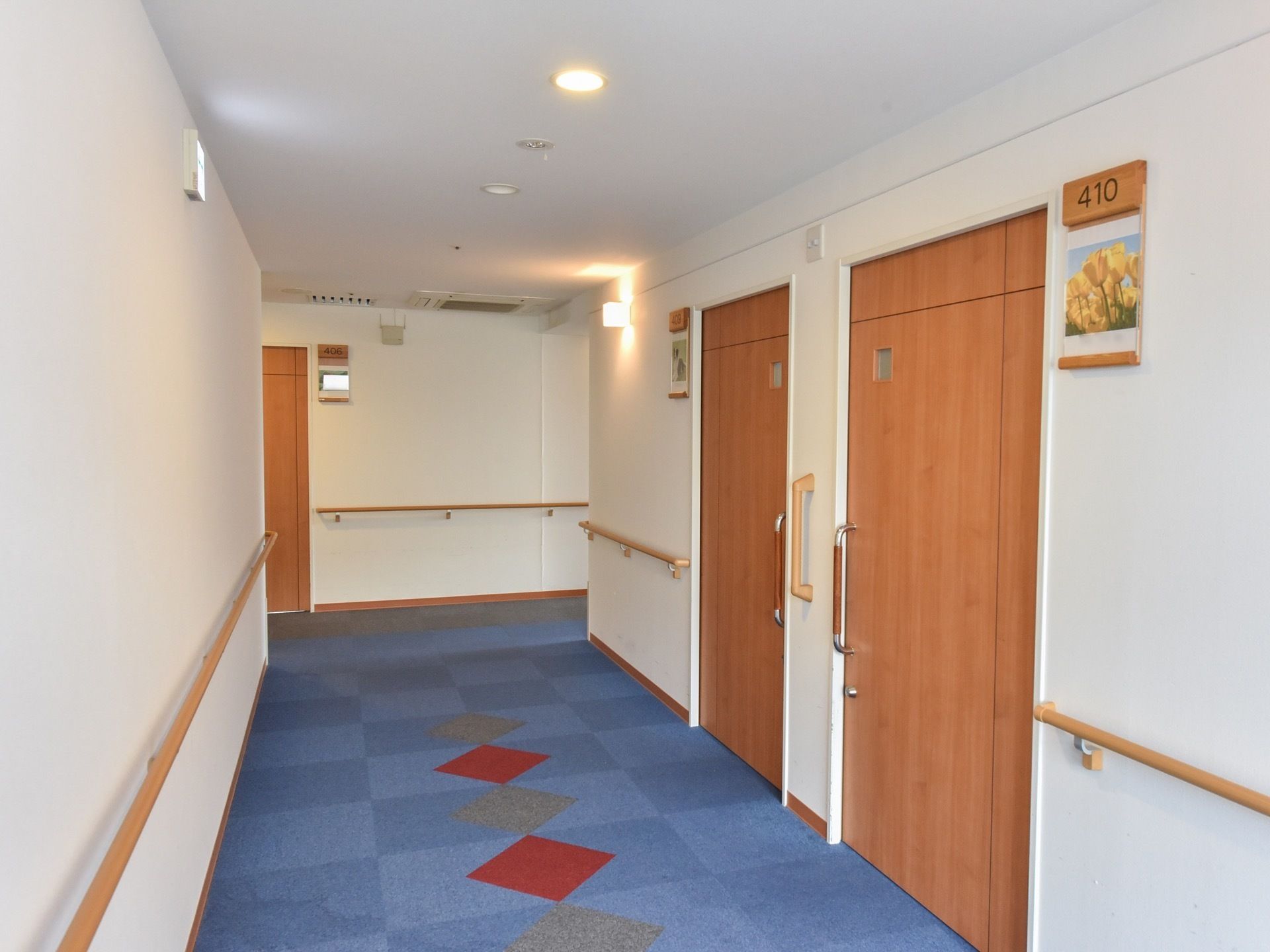 居室が立ち並ぶ清潔感のある廊下。扉や手すりは木製となっており、各部屋は鍵が掛けられるようになっている。
