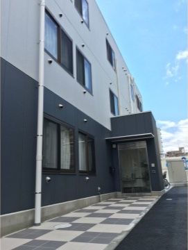 施設の建物はシンプルでモダンな造りで、壁面は白と黒の２色である。認知症の入居者様も安心して生活することができる。