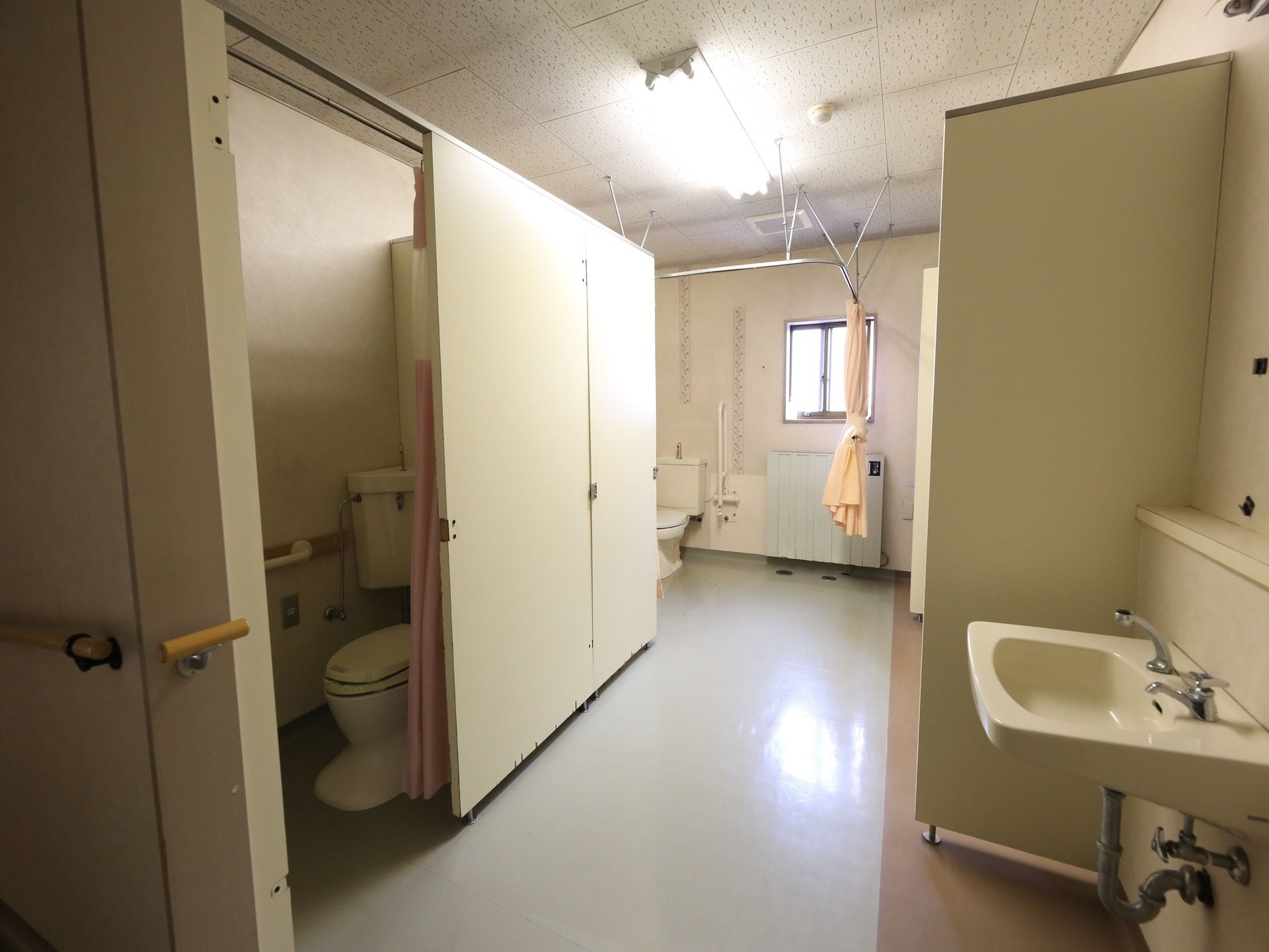 トイレの仕切りは、カーテンが使われている。車椅子に乗った状態で移動がしやすいよう、トイレ内や洗面台の周囲にはスペースが広く取られている。