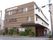 道路側から見た建物の壁面は、茶色い横長のパーツで覆われている。一方、2、3階は普通の白い壁である。少し奥まったところに入り口がある。
