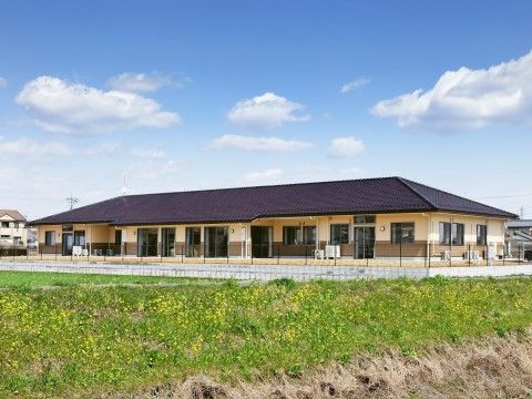 ベージュの壁に切妻屋根が載ったまだ新しい建物で、敷地の周りには低いブロックを土台に、フェンスが設置されている。