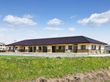 ベージュの壁に切妻屋根が載ったまだ新しい建物で、敷地の周りには低いブロックを土台に、フェンスが設置されている。