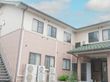 ベージュとレンガ調の壁のツートンカラーが目を引く２階建ての建物。少し高い位置にあるので２階でも見晴らしがよく日当たりもよい。
