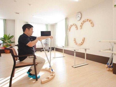 運動器具のある部屋で椅子に座りトレーニングをする男性