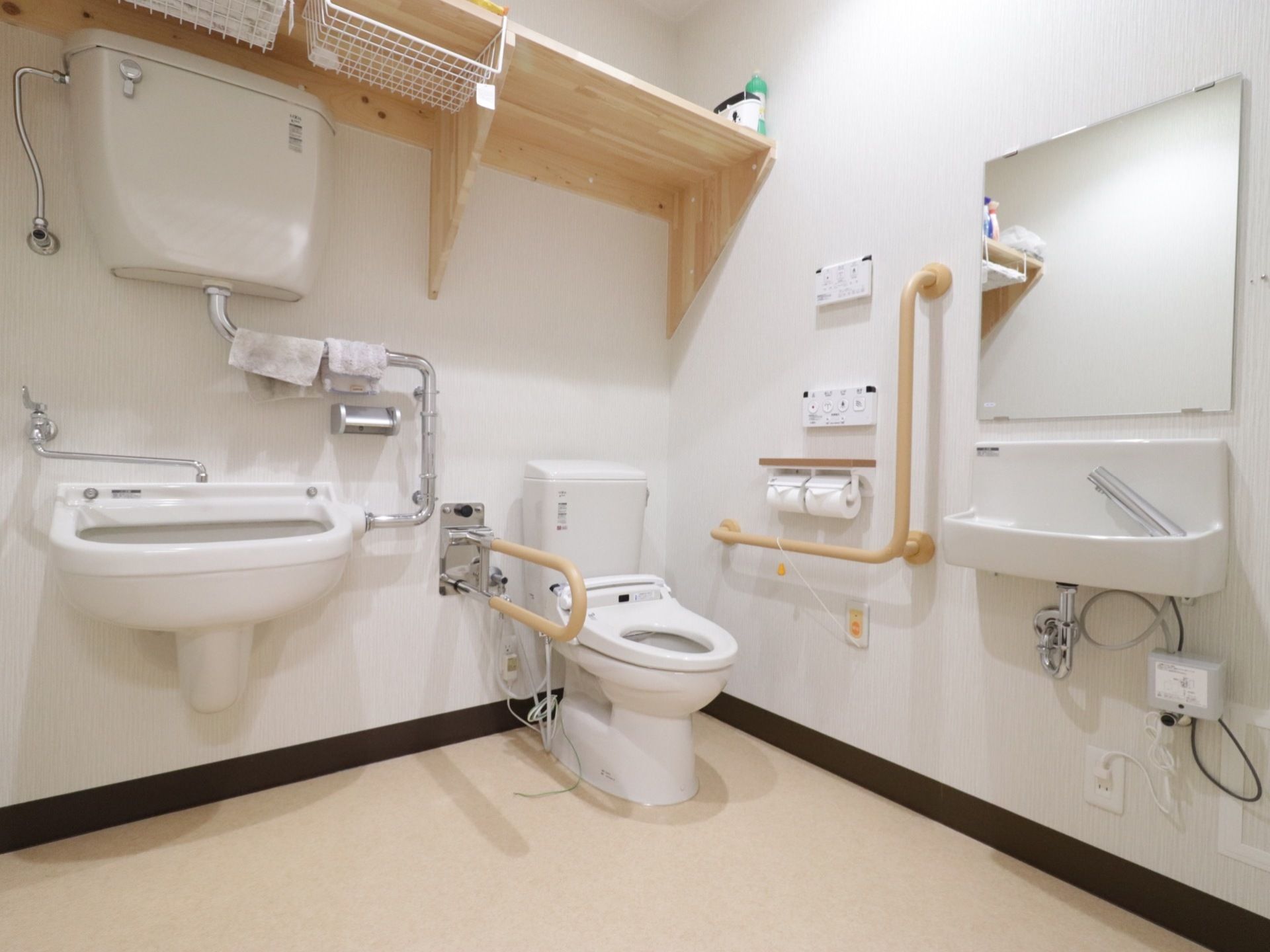 温水洗浄便座付きのトイレである。脇には多機能洗浄台が備わっている。雑巾が干してあり、上部には棚が設置されている。