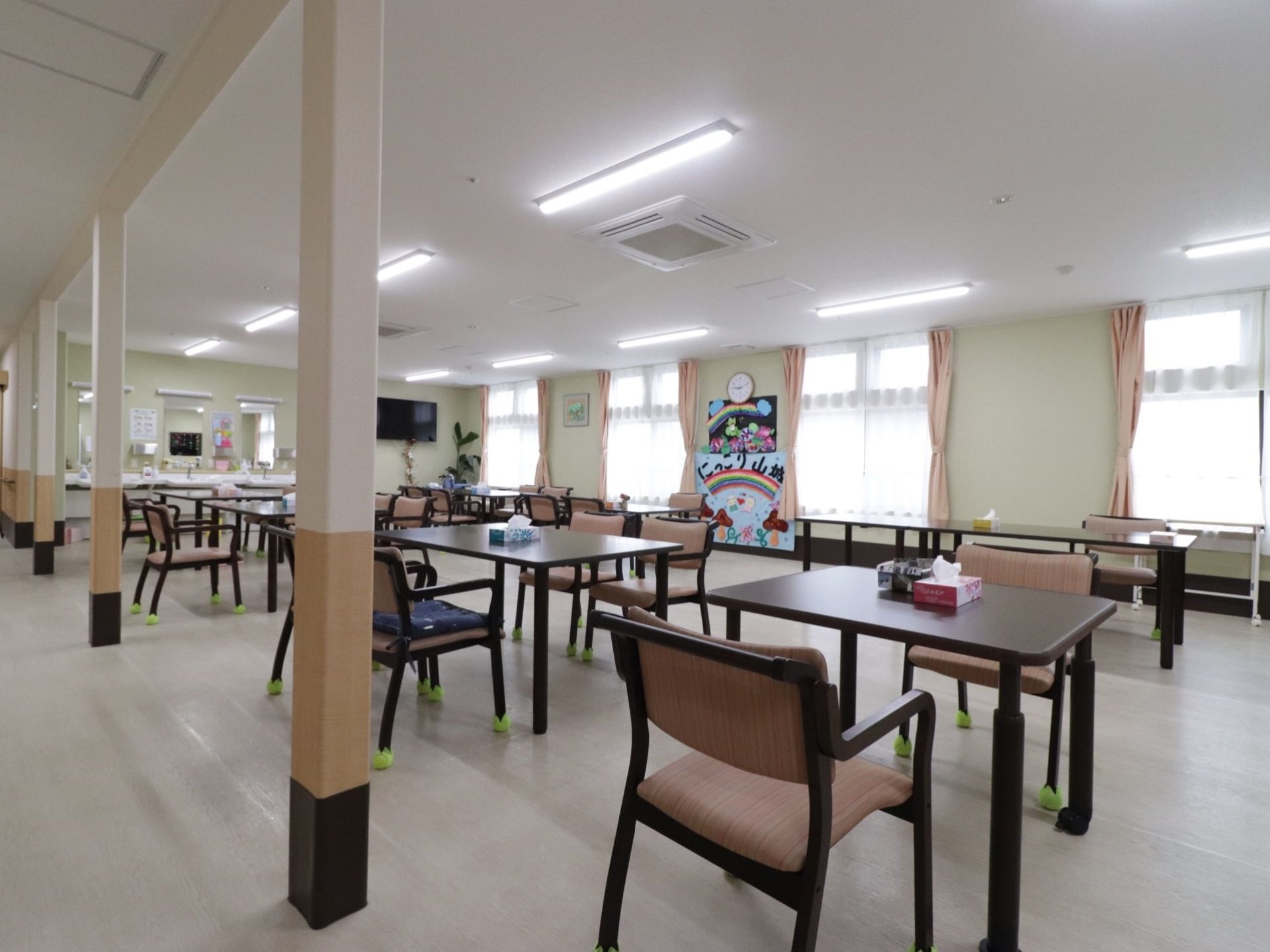見晴らしが良い明るい空間に、高級感のある茶系のテーブルと椅子のセットが均等な空間を空けて綺麗に並んでいる。
