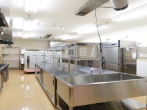 ステンレス製の大きな調理台と流し台が中央にある、広い調理室