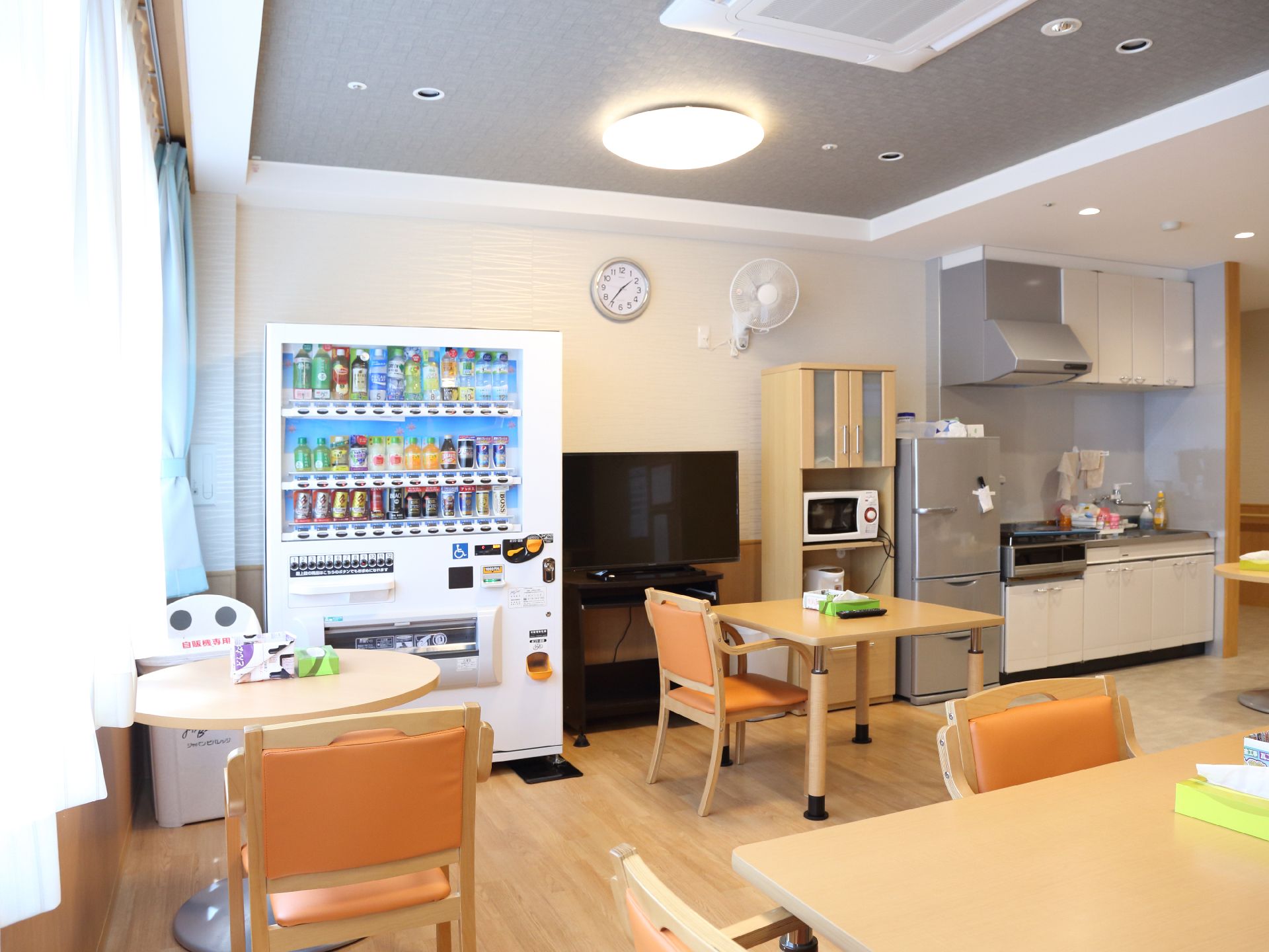 共有部屋には、テレビ、冷蔵庫といった家電の他、自動販売機とキッチンがある。テーブルセットもあり、飲食ができるスペースである。