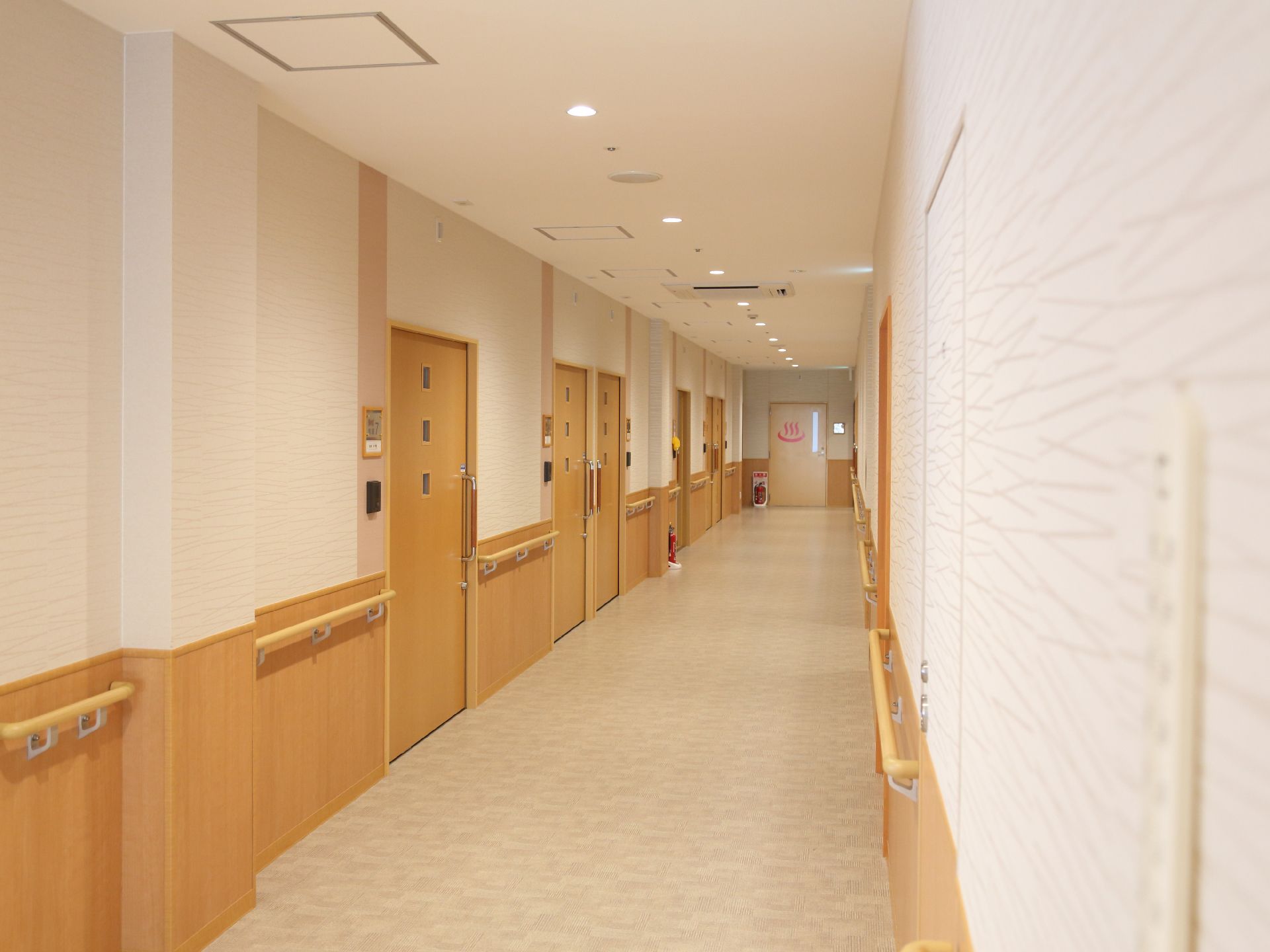 廊下には手すりが渡されていて、突き当たりのドアには温泉マークが描かれている。廊下の途中には、消火器が置いてある。