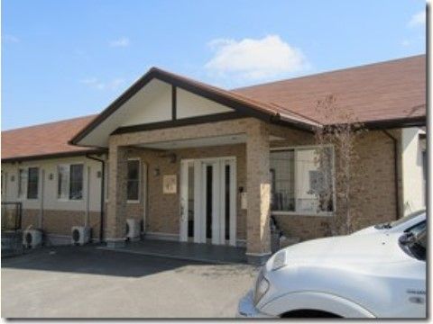 手前に車が停まっており、庇部分が三角屋根になっている平屋建て