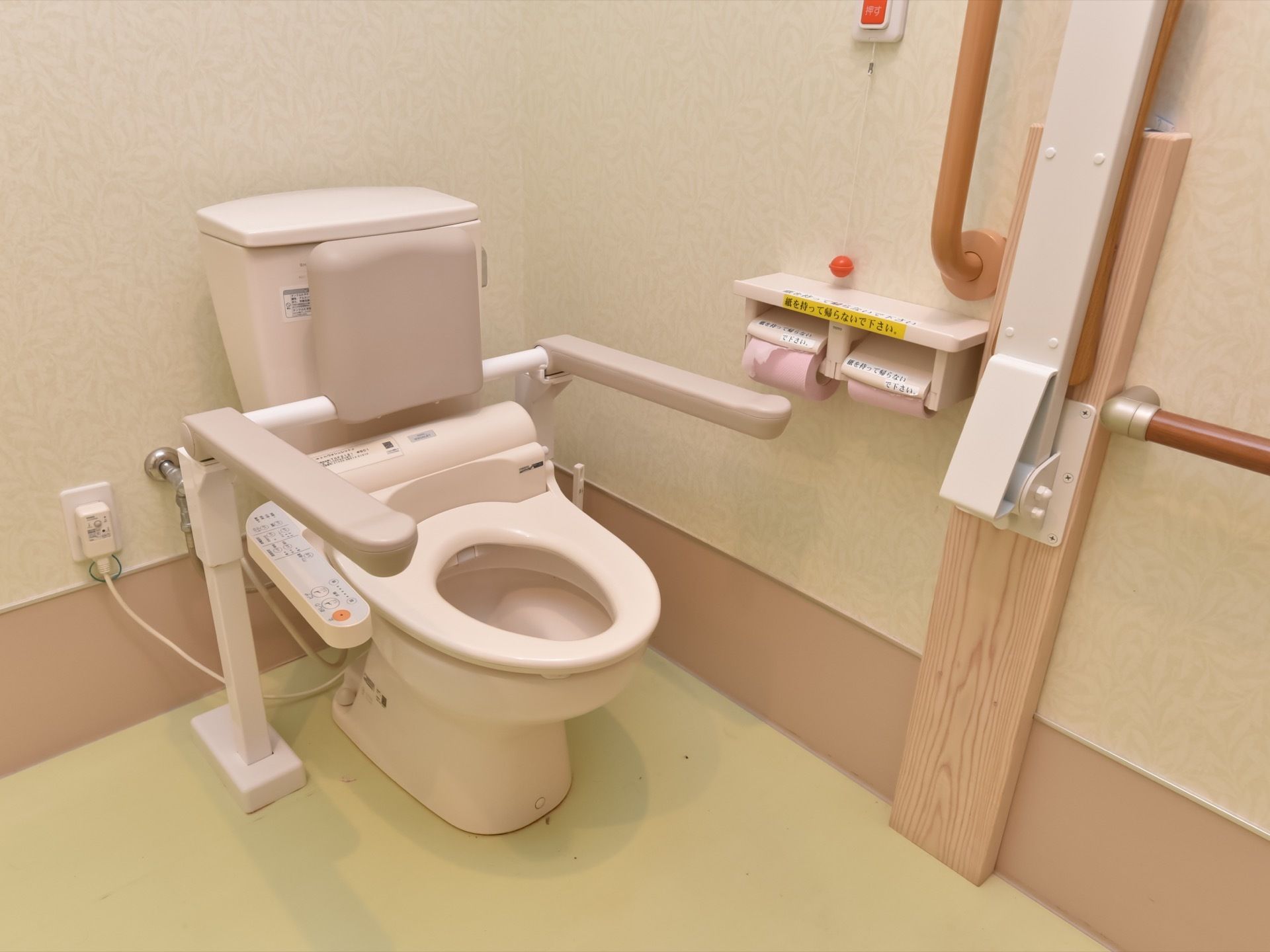 車椅子に対応した広めの作りの部屋をしたトイレ。温水洗浄機能の付いた便座が設置されており、コントローラーは右手側にある。