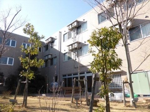 庭にベンチが置かれ、木が何本か植えられている三階建ての建物