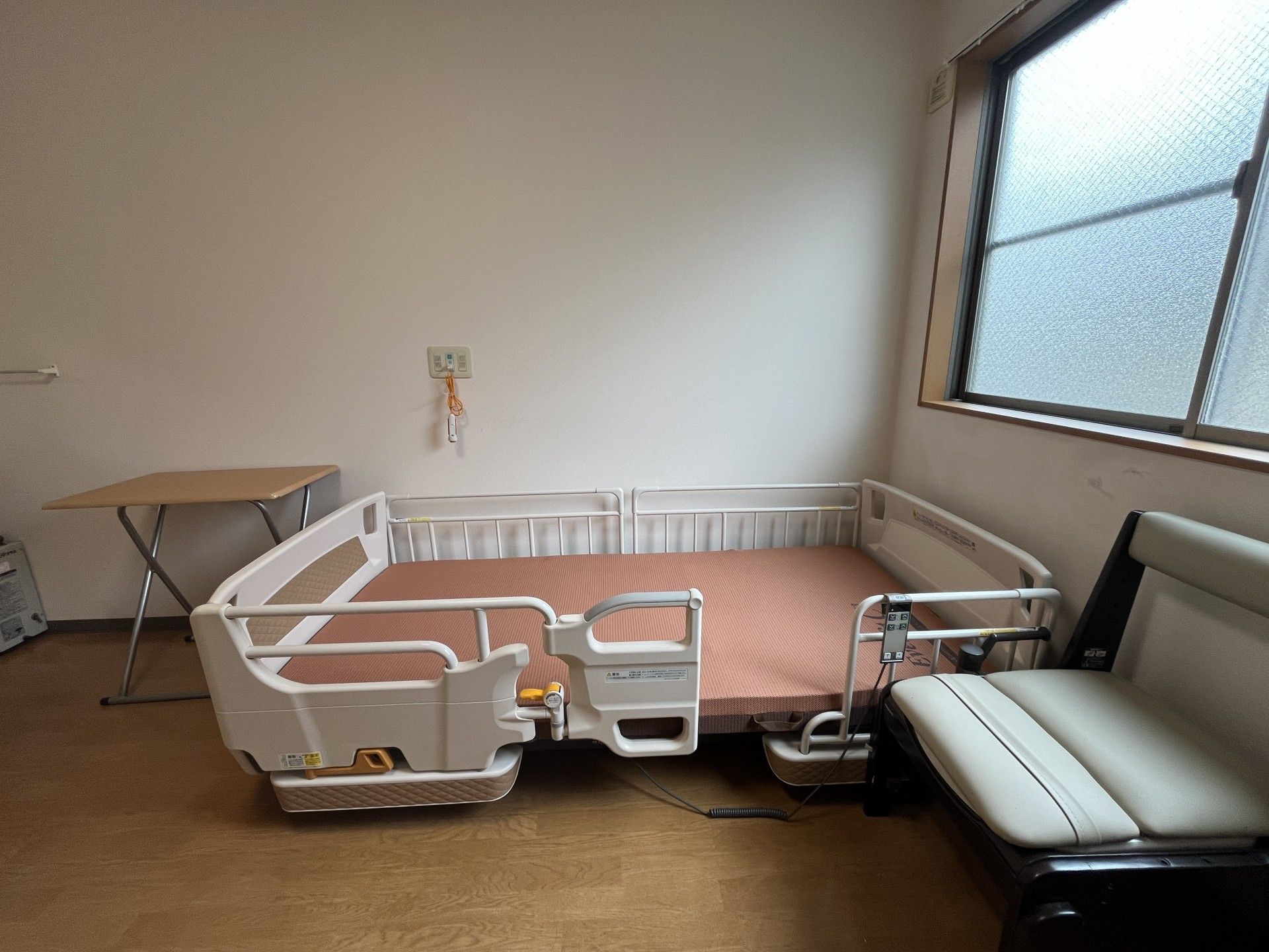 手すりにつかまり車に乗る高齢男性と介助をするヘルパー