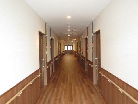 フローリングの通路は一直線に長く伸びている。壁の下半分は木目調になっていて、あたたかさを感じる。手すりも付いているので安心して歩行できる。