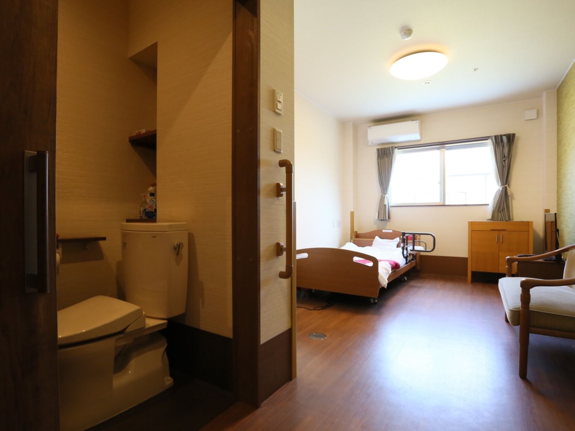 居室内にはトイレが併設されており、木目の引き戸で開閉しやすい。リビングは広くベッドや家具を置いても、車椅子や歩行器を置くことができる。