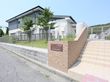 道路から階段を登ったところにある施設である。塀に施設名の書かれた看板が取りつけられており、上は芝生になっている。