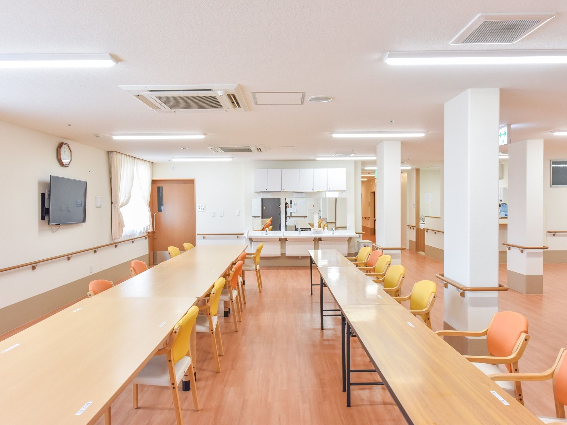食堂の中央には、黄色とオレンジ色の椅子と長机が2列に並べられている。壁際には、3つの洗面台が設置されている。