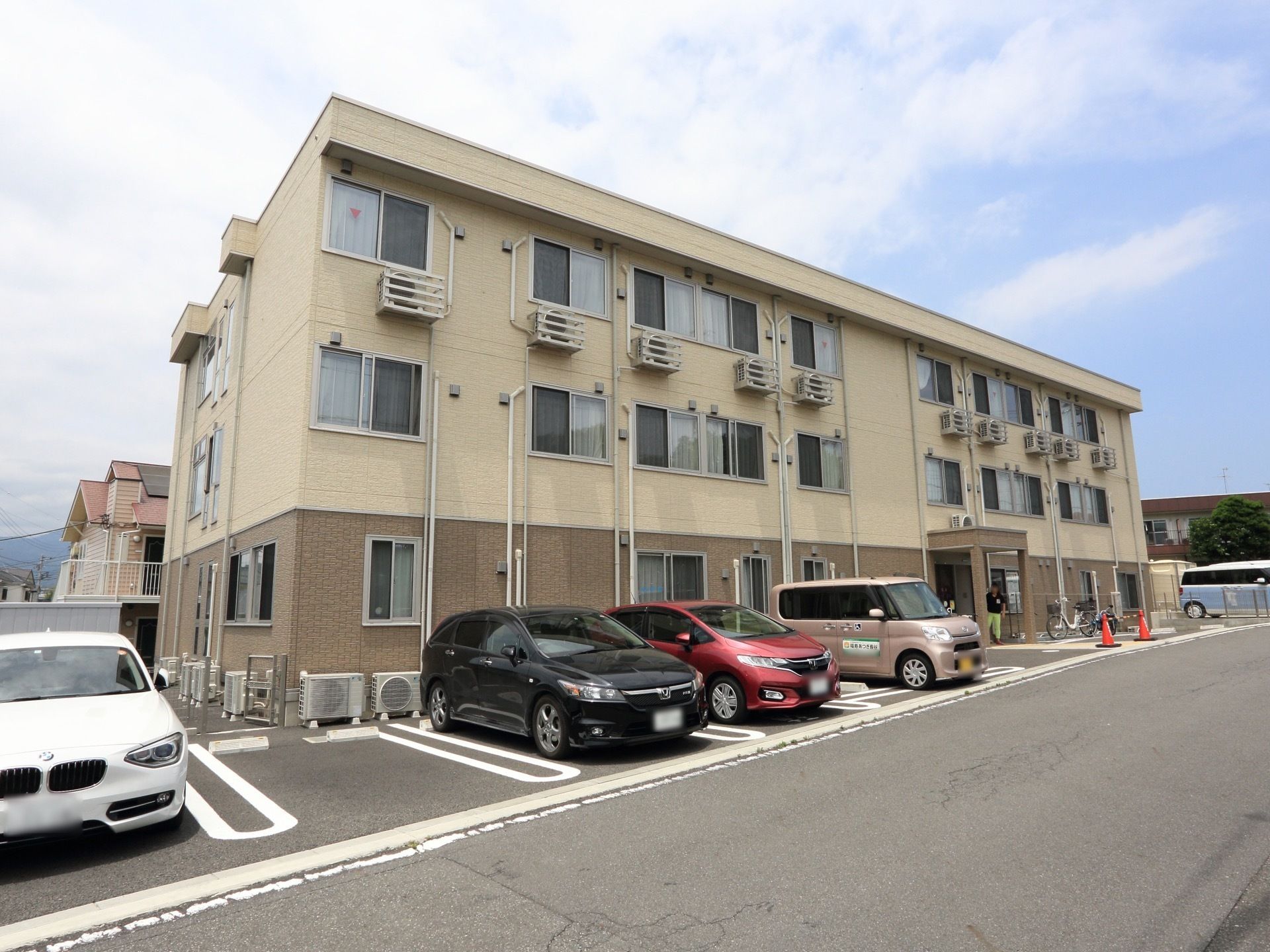 鉄骨3階建ての施設である。落ち着いたツートンカラーで施されており、親しみやすいデザイン。駐車場も完備している。
