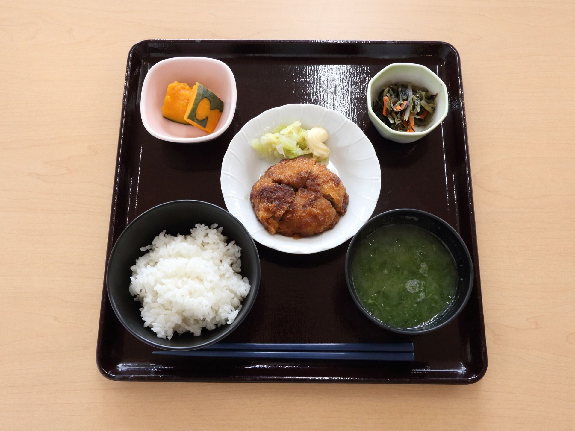 黒色の正方形のトレーに彩りのよい食事がならべられている。この日は白ご飯と汁物、おかずや小鉢が提供されている。