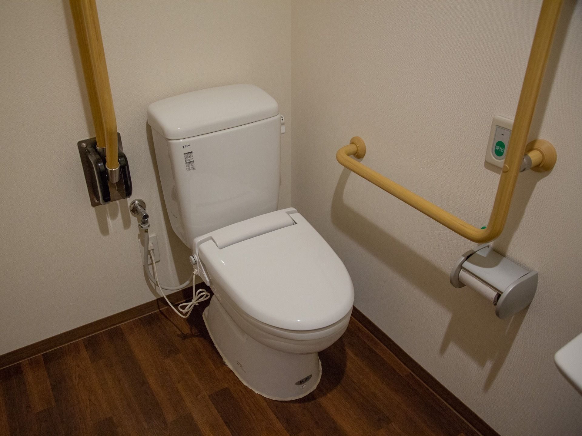 呼出ボタンがあるトイレ。縦横両方向に手すりがあり、安全にどなたでも利用できる。トイレ自体は一般的なものである。
