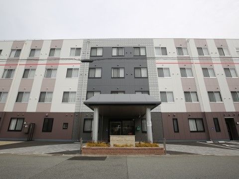 正面に駐車場と車寄せがあり、等間隔に窓が見える建物