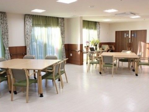 柄があるカーテンが取り付けられていて、机を囲むように椅子が配置されたリビング