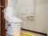 引き戸で出入りできるトイレである。壁にはナースコールや手すりが設置されている。暖房便座のトイレである。