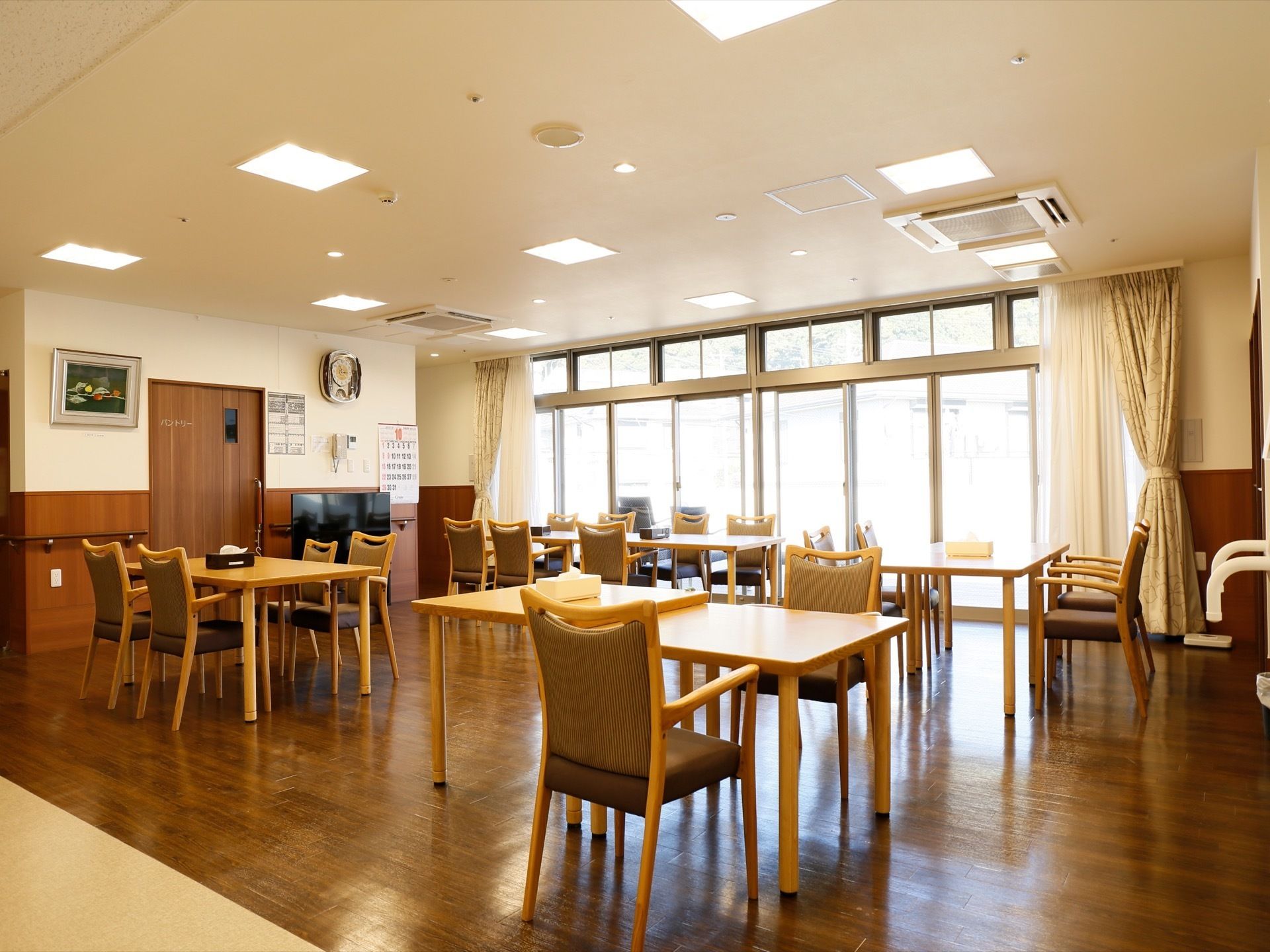 床の色がダークブラウンになっている部分が食堂で、テーブルや椅子が並べられている。左側にはパントリーの扉がある。