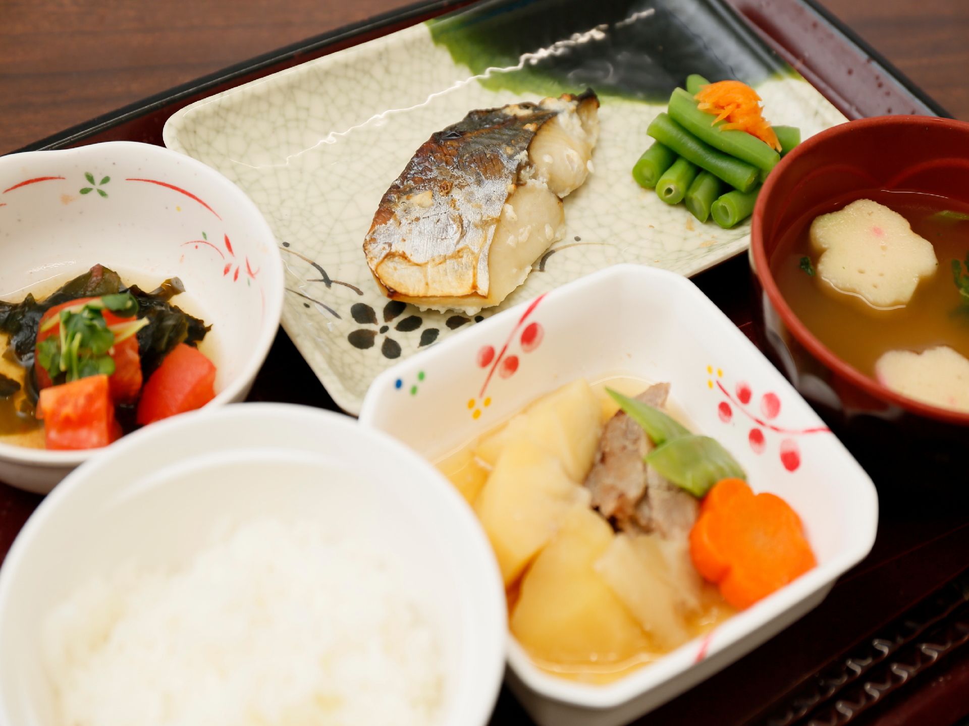 焼き魚や煮物、汁物が柄のあるお皿に盛り付けてある和食のお膳