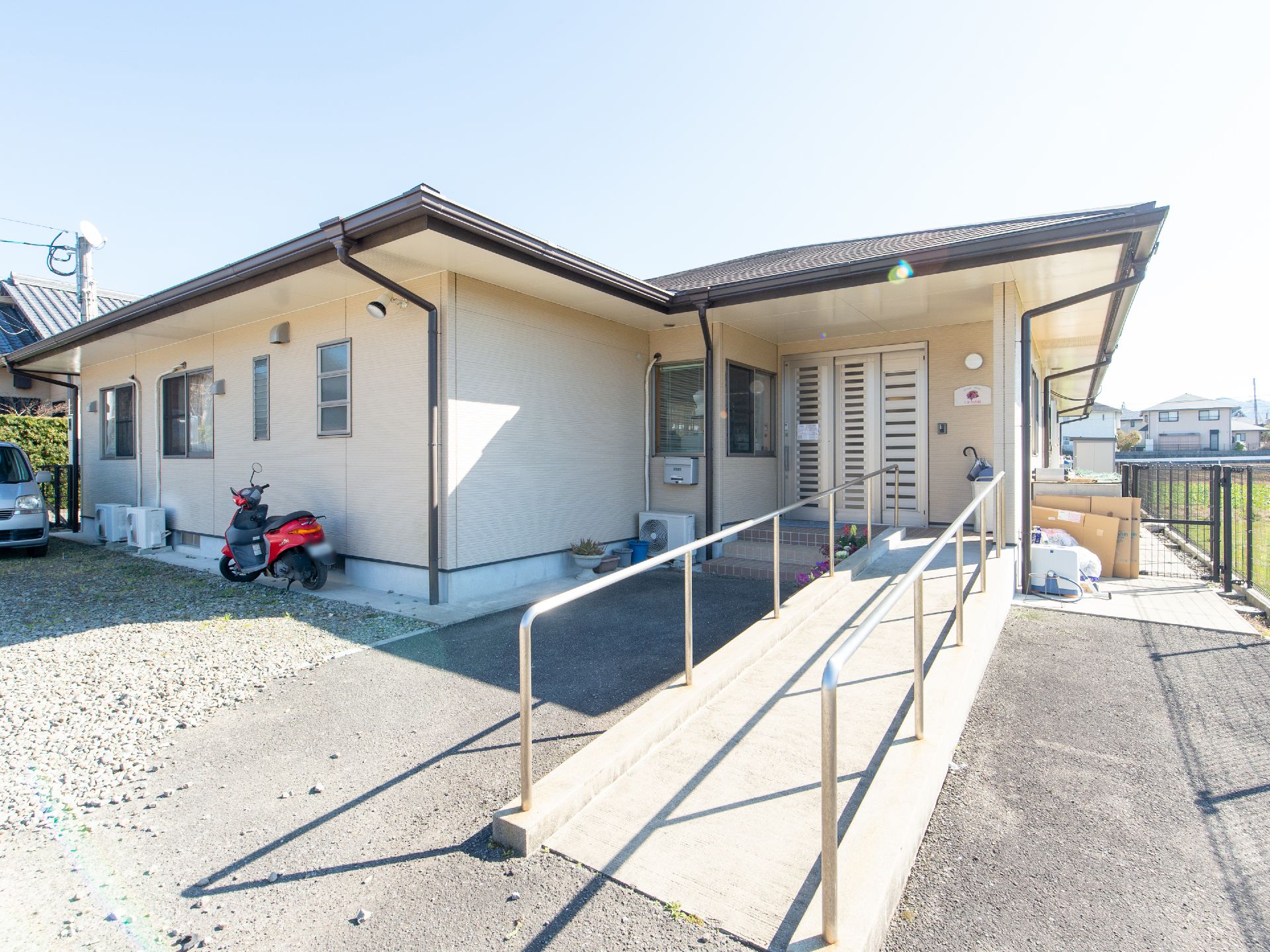 白色の外壁が特徴的な平屋建ての施設である。玄関前には緩やかなスロープがあり、その両脇には切れ目のない手すりがある。