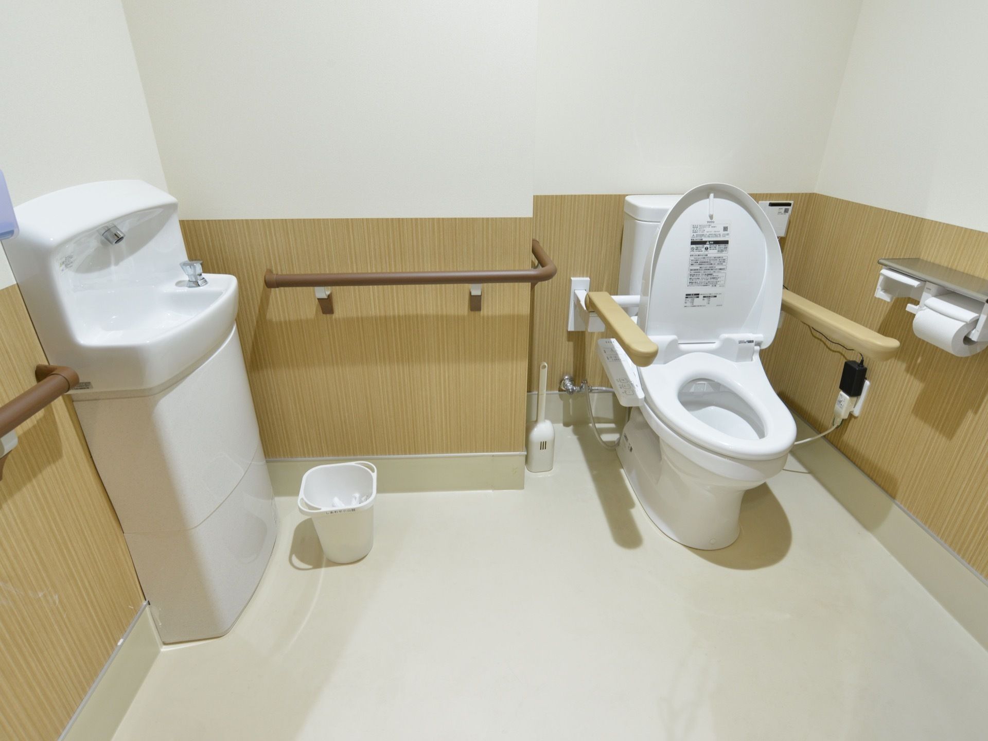 清潔感のあるトイレには温水洗浄便座が設置されている。肘置きもあるので立ち上がる時の補助として使える。横に手洗い場がある。